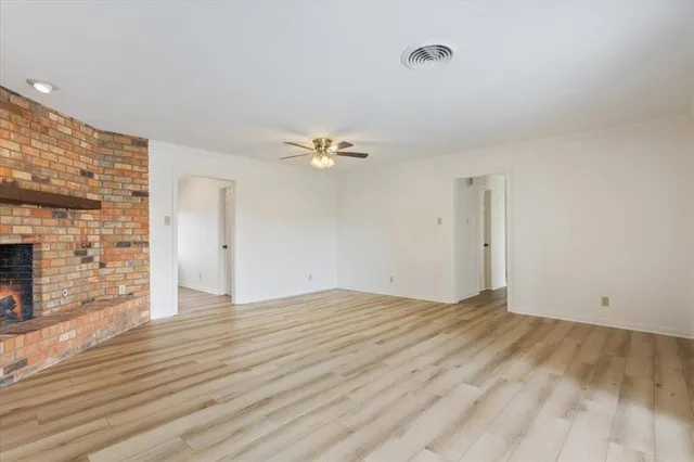 a view of an empty room with wooden floor and a fireplace