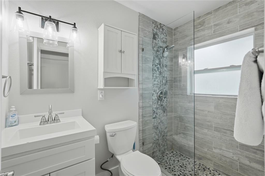15424 2nd Street East Madeira Beach, FL 33708 - Photo 12 of 30 a bathroom with a shower a sink a toilet and a mirror