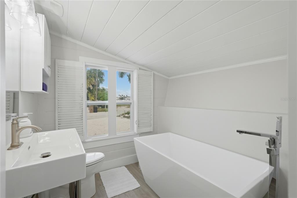 15424 2nd Street East Madeira Beach, FL 33708 - Photo 17 of 30 a bathroom with a bathtub a sink a toilet and a window
