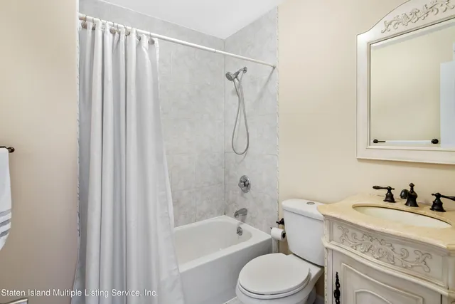 a bathroom with a granite countertop bathtub shower sink vanity mirror and toilet