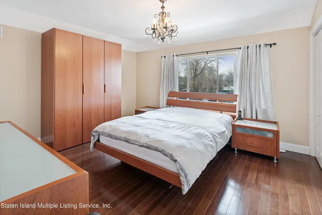a bedroom with a bed wooden floor and window