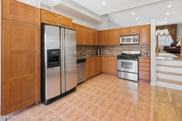 a kitchen with stainless steel appliances granite countertop a refrigerator and a stove top oven