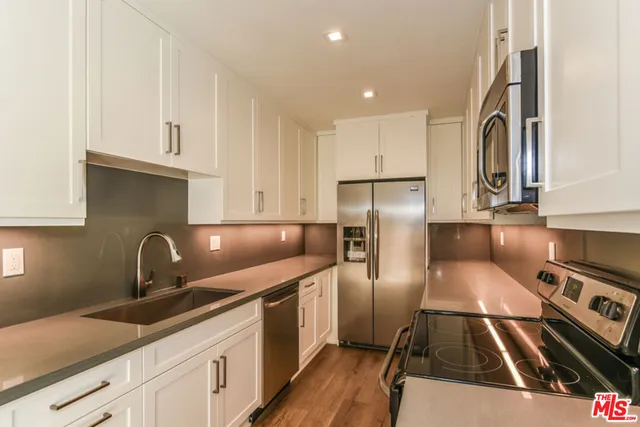 a kitchen with granite countertop a sink stainless steel appliances and cabinets