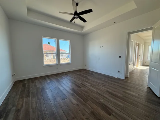 an empty room with wooden floor ceiling fan and windows