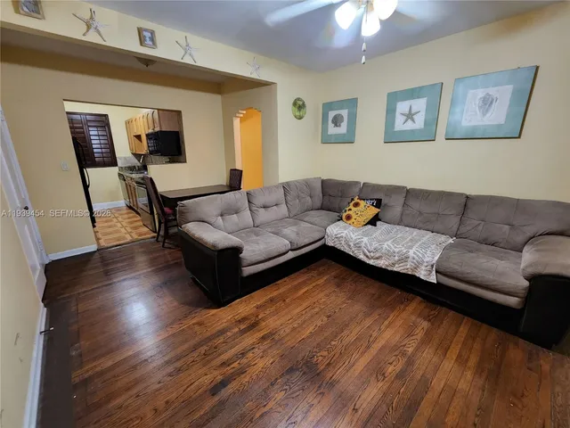 a living room with couches and a dining table with wooden floor