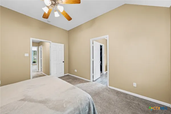 an empty room with chandelier fan and windows