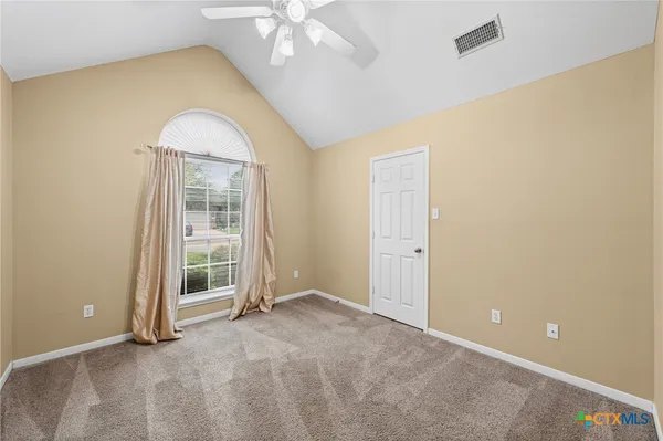 a view of an empty room with a chandelier fan