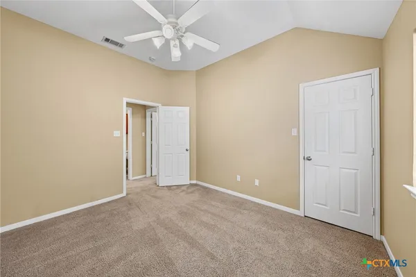 a view of an empty room with window and chandelier fan
