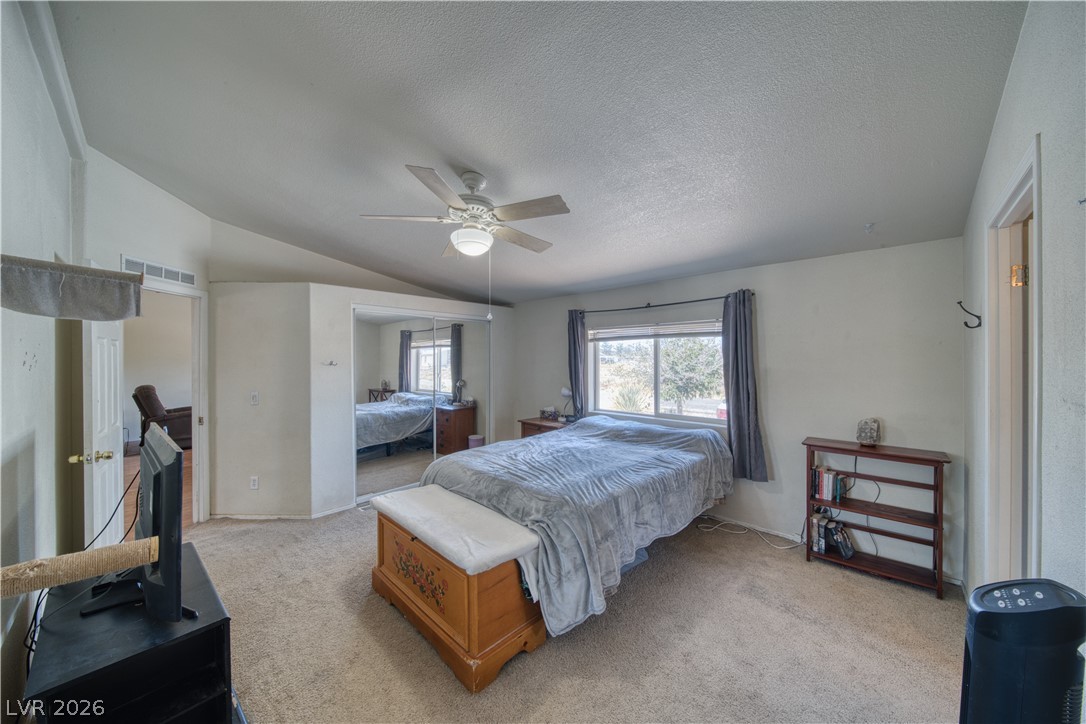2931 Rio Rancho Drive, Unit 4 Pahrump, NV 89048 - Photo 10 of 21 A comfortable bedroom with vaulted ceilings features a large mirrored closet and a window view.