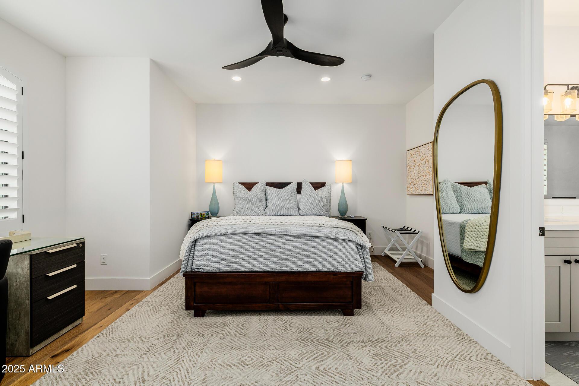 7245 North 13th Lane Phoenix, AZ 85021 - Photo 18 of 40 a spacious bedroom with a bed a mirror on dresser and a wooden floor