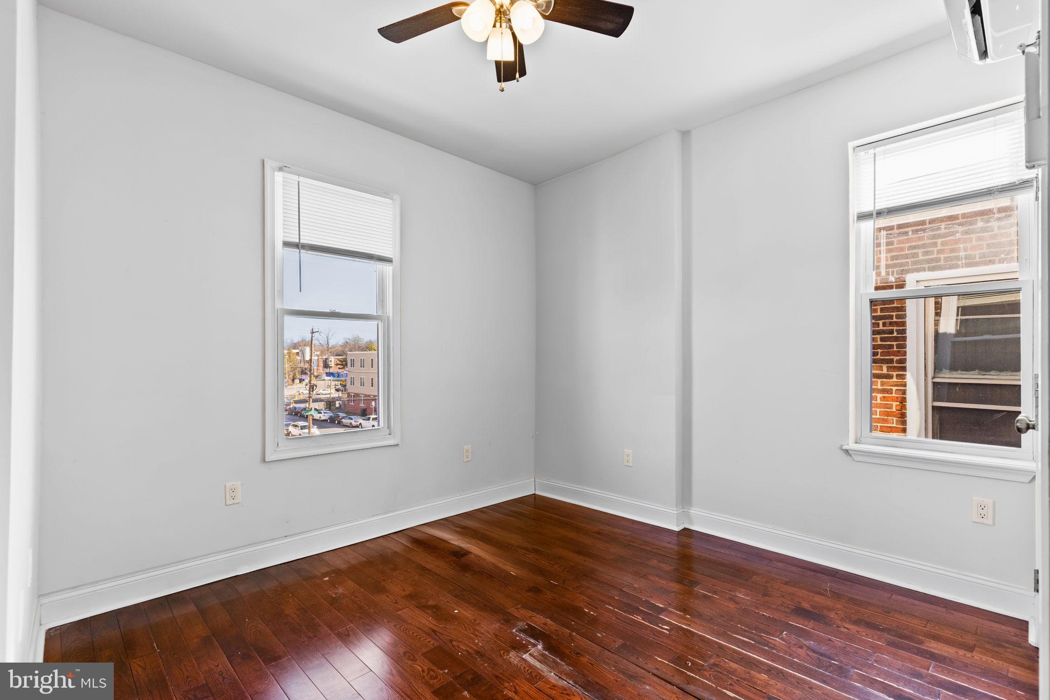 4633 Walnut Street, Unit D Philadelphia, PA 19139 - Photo 6 of 10 an empty room with wooden floor chandelier fan and windows