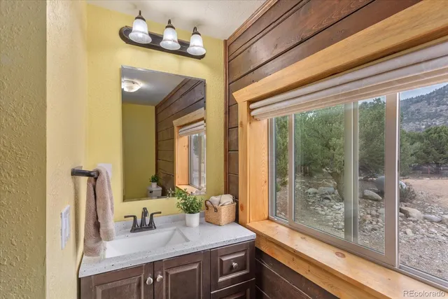 a bathroom with a granite countertop sink and a large mirror