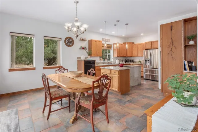 a dining room filled with furniture a chandelier and kitchen view