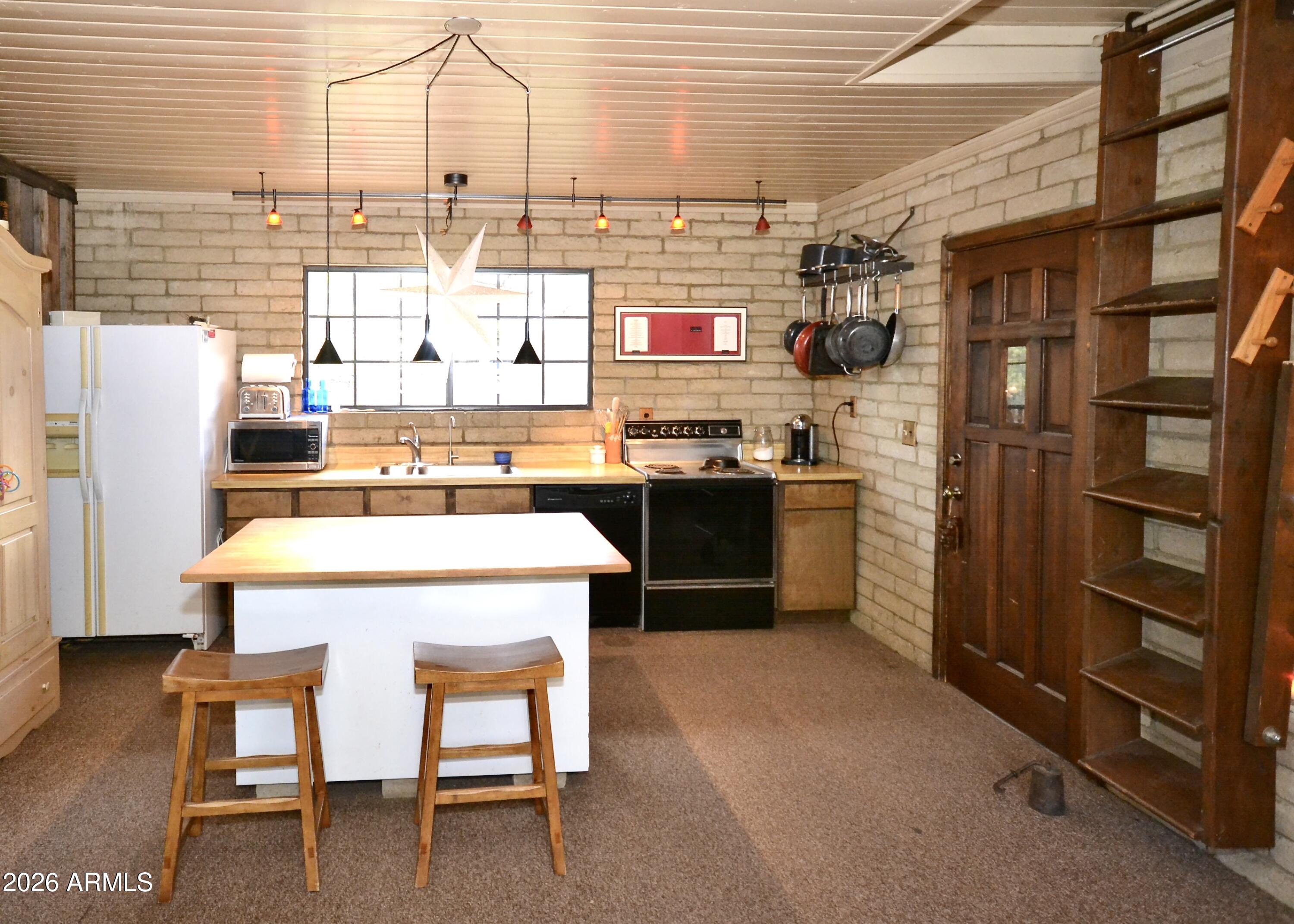 23617 South Demascus Road Crown King, AZ 86343 - Photo 26 of 50 a kitchen with stainless steel appliances kitchen island granite countertop a table chairs and a refrigerator