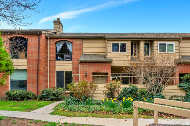 Brick and siding exterior featuring arched windows, a chimney, and a second-story balcony