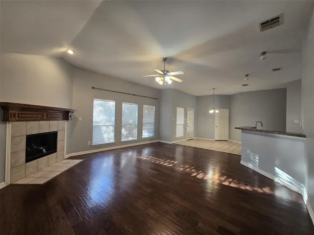 a view of an empty room with wooden floor and a fireplace