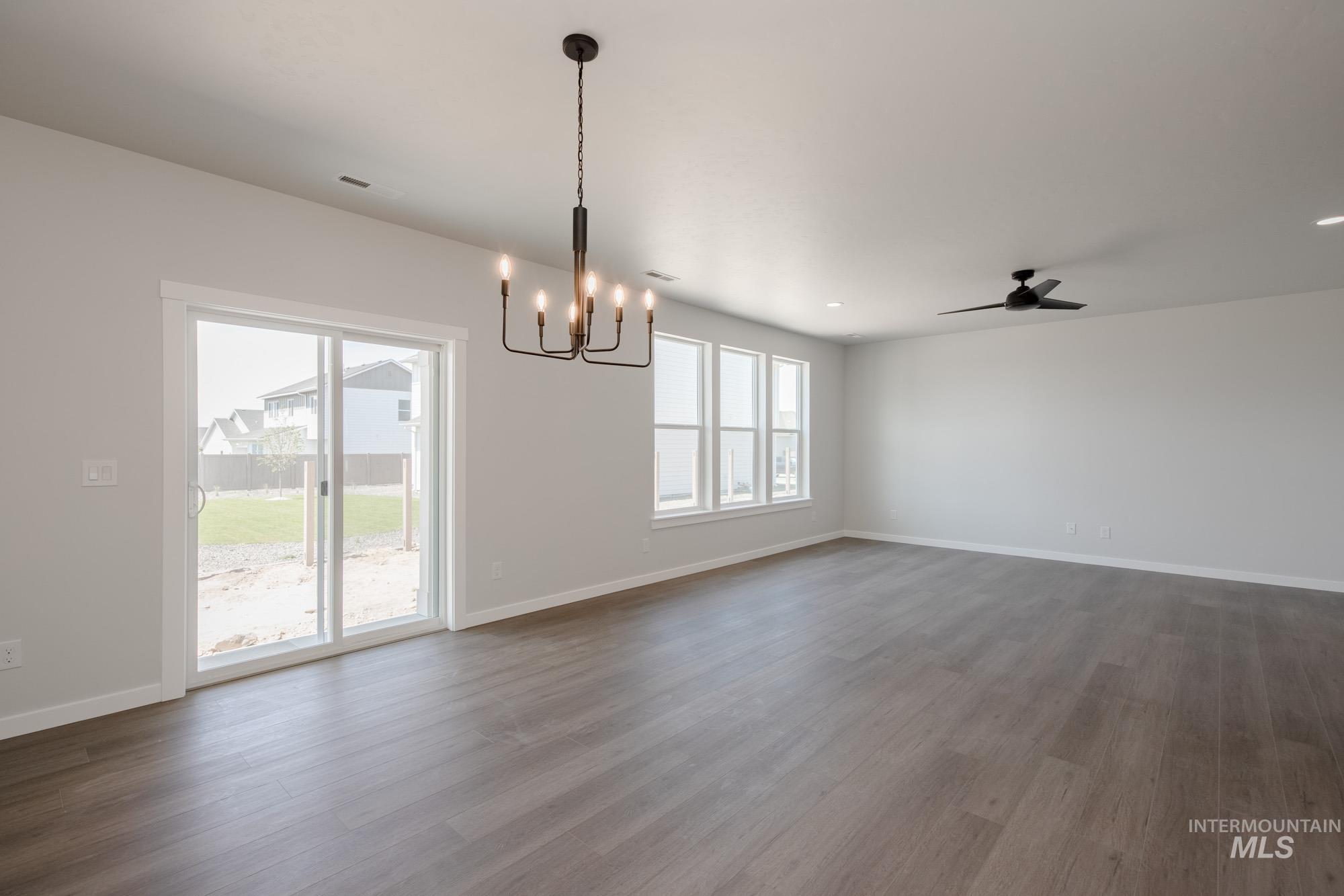 6447 South Sunfish Way Boise, ID 83709 - Photo 11 of 29 Unfurnished dining area with a chandelier, dark wood-style flooring, and ceiling fan