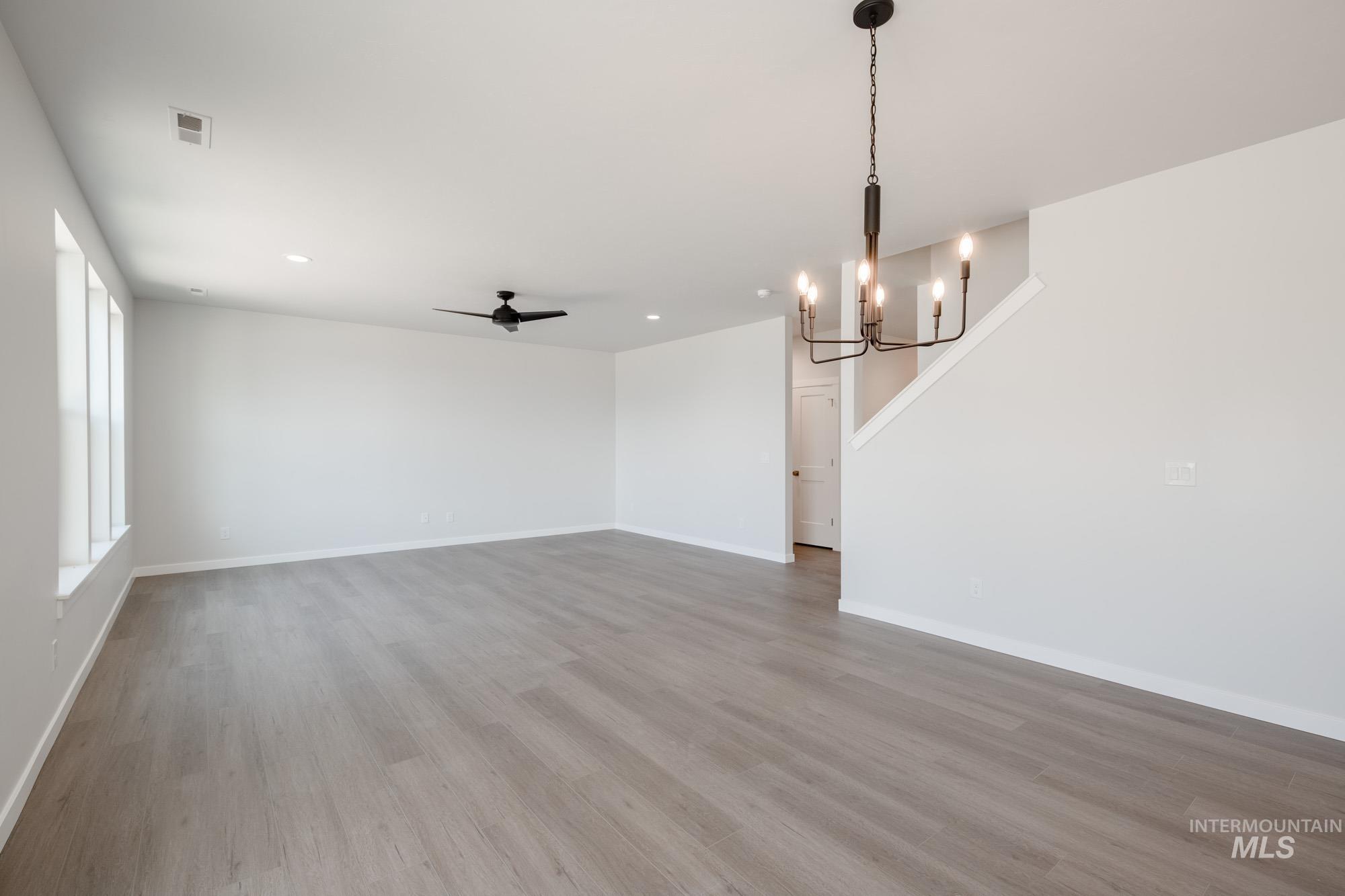 6447 South Sunfish Way Boise, ID 83709 - Photo 12 of 29 Unfurnished living room with a ceiling fan, a chandelier, wood finished floors, and recessed lighting