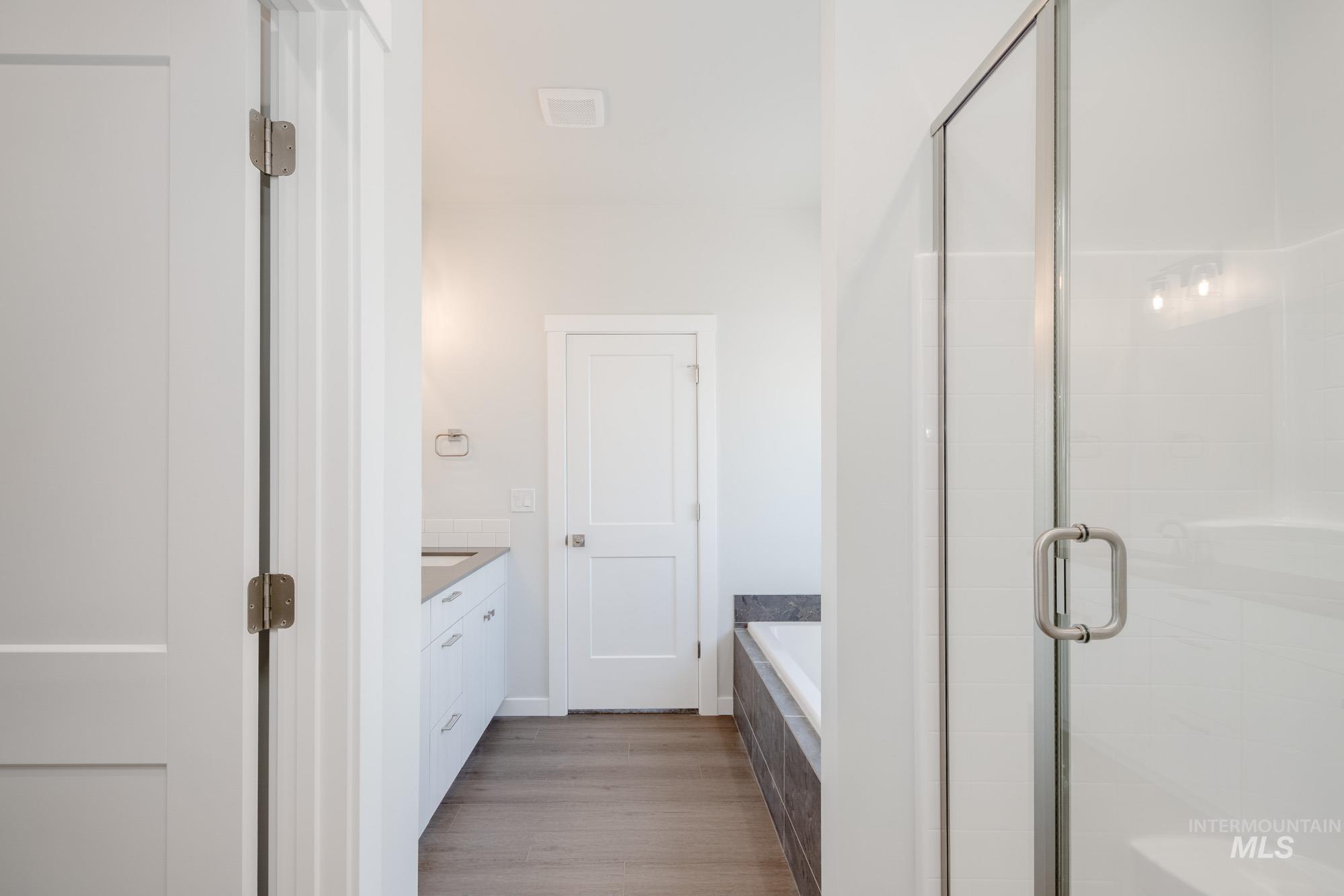 6447 South Sunfish Way Boise, ID 83709 - Photo 20 of 29 Full bath featuring a bath, a stall shower, wood finished floors, and vanity