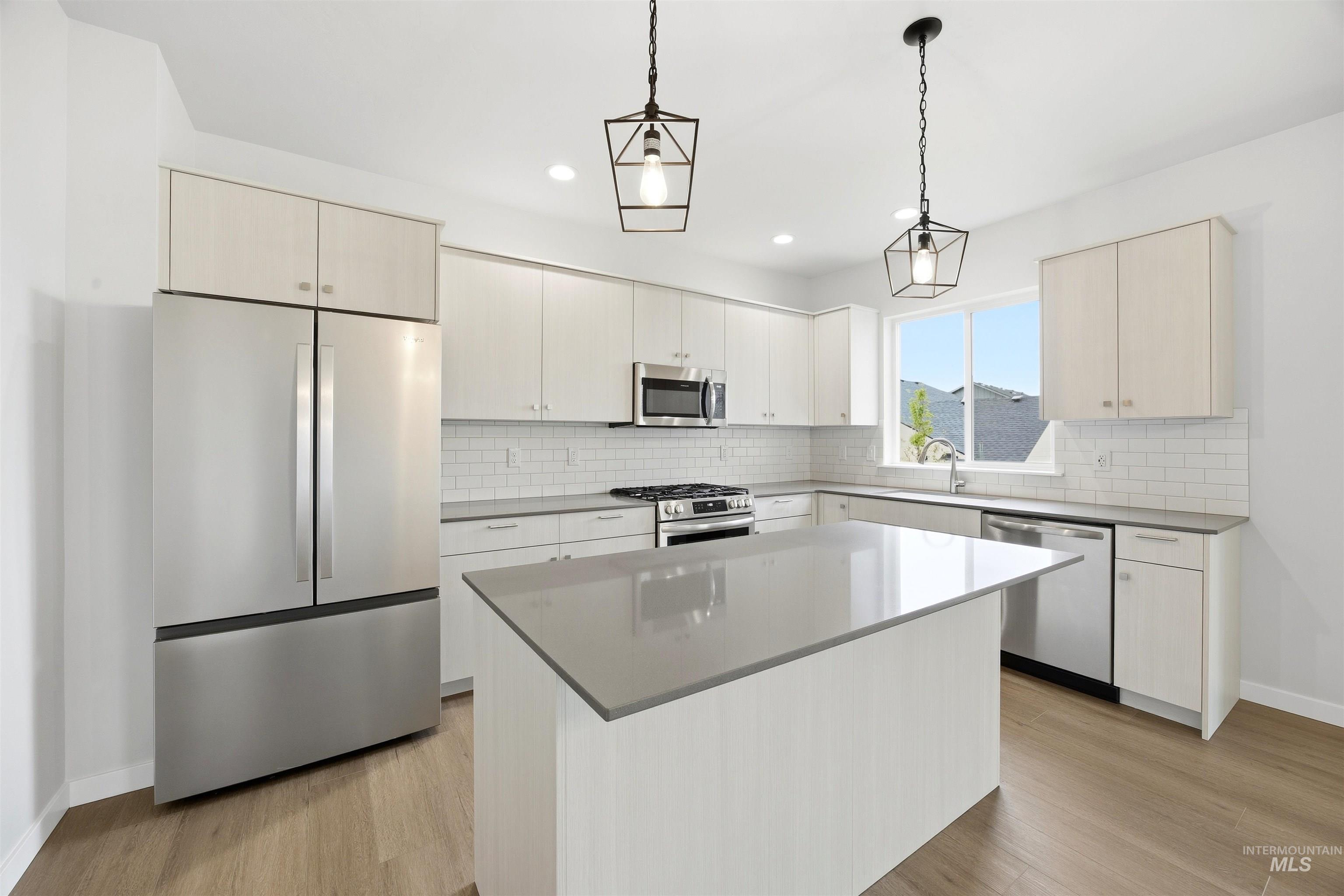 6447 South Sunfish Way Boise, ID 83709 - Photo 5 of 29 Modern kitchen with light wood-finish flooring, featuring a central island with a solid surface countertop