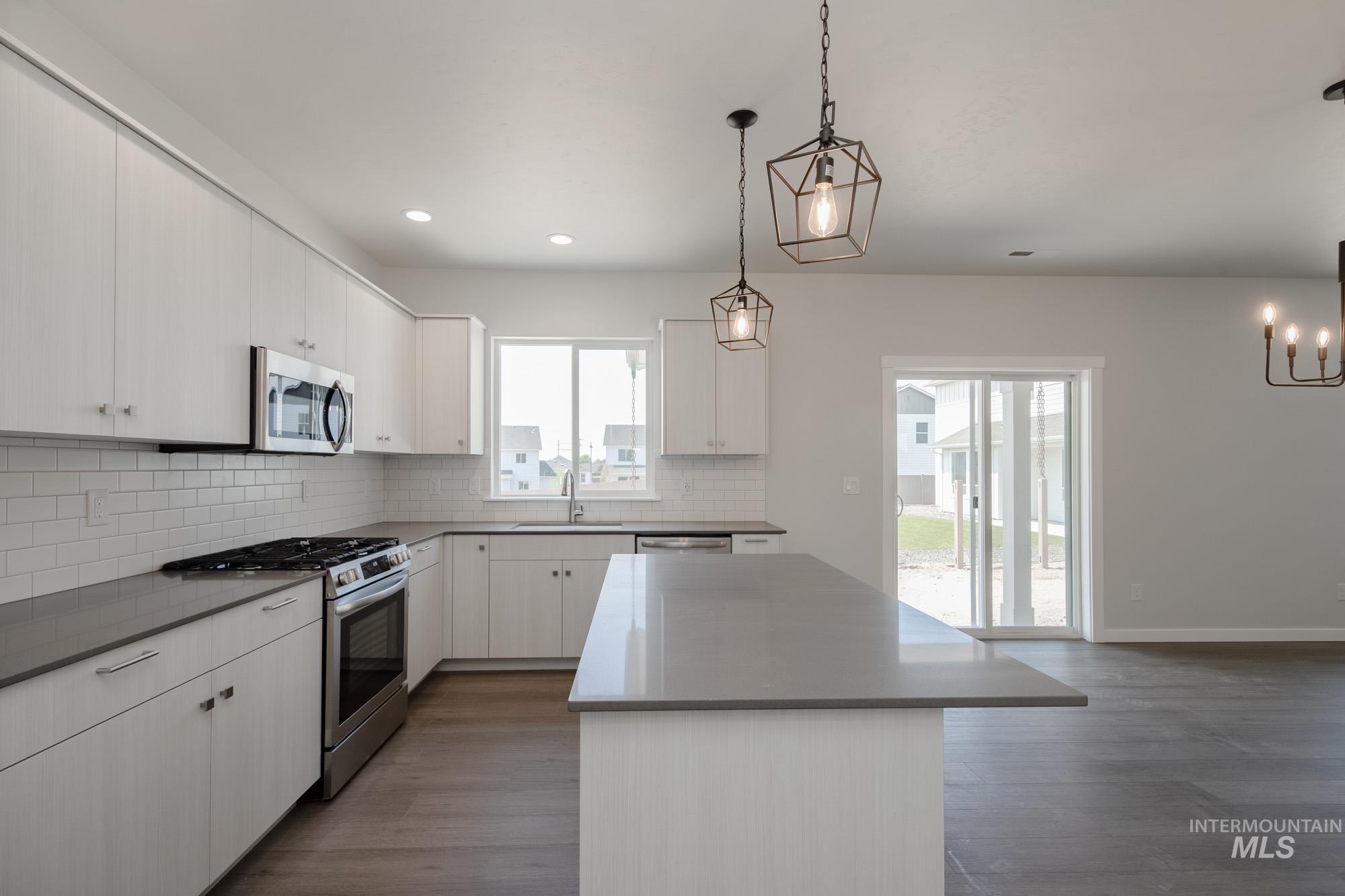6447 South Sunfish Way Boise, ID 83709 - Photo 8 of 29 Kitchen with stainless steel appliances, backsplash, a kitchen island, dark wood-type flooring, and hanging light fixtures