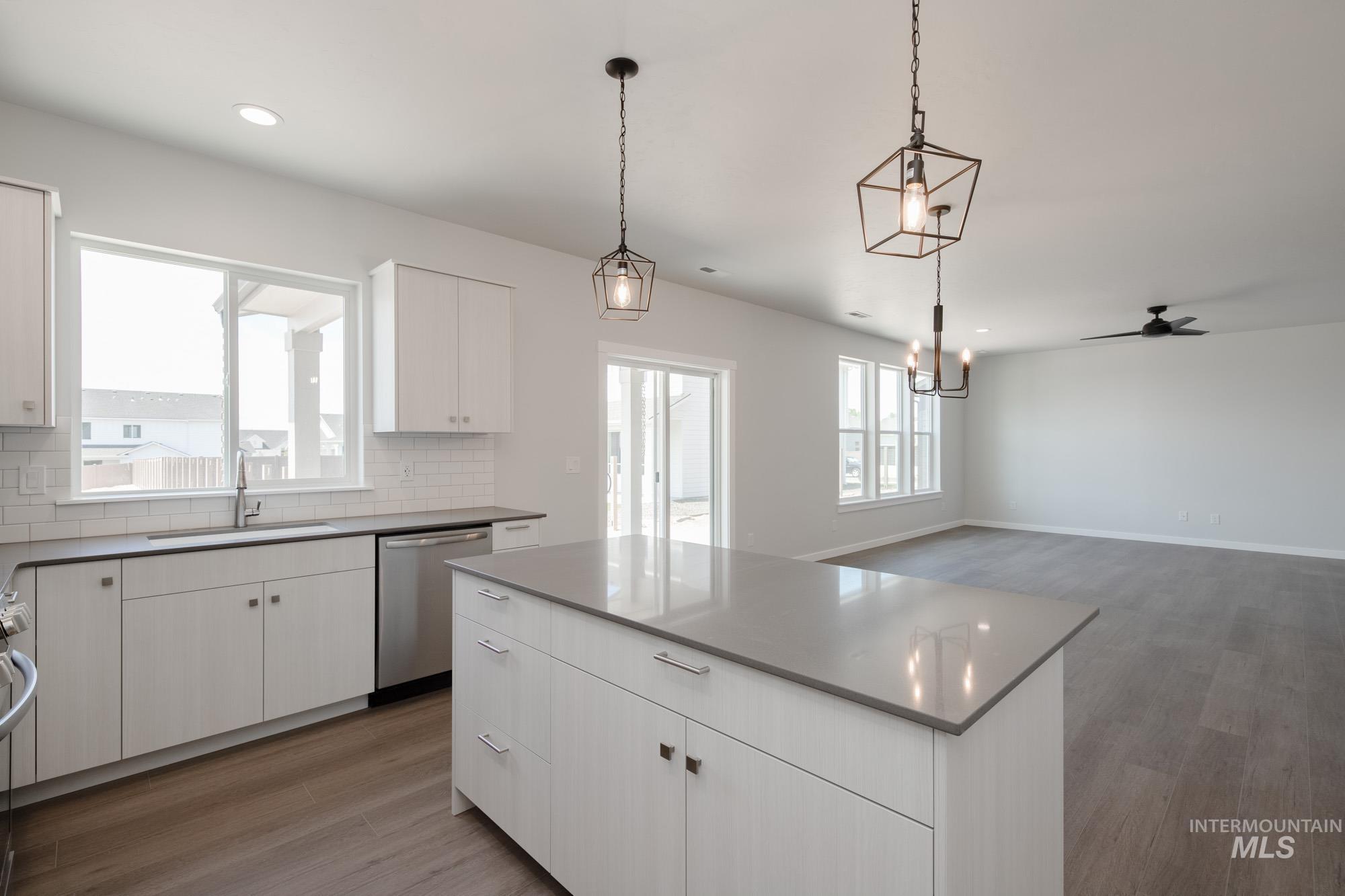6447 South Sunfish Way Boise, ID 83709 - Photo 10 of 29 Kitchen with ceiling fan, wood finished floors, a kitchen island, stainless steel dishwasher, and decorative backsplash
