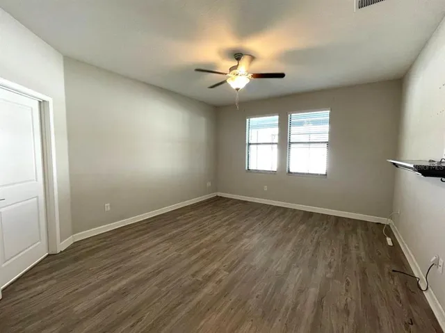 an empty room with wooden floor and a ceiling fan