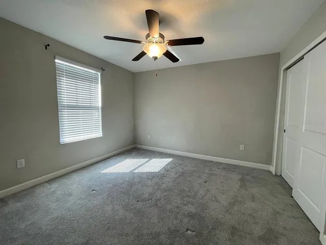 an empty room with wooden floor fan and windows
