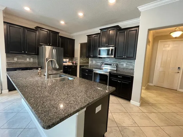 a kitchen with kitchen island granite countertop a sink stove and refrigerator