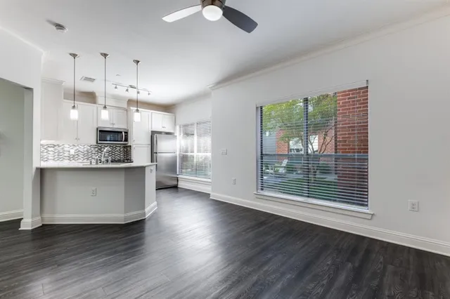 a kitchen with stainless steel appliances kitchen island wooden floors cabinets and a chandelier