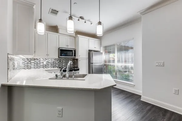 a kitchen with a sink stainless steel appliances and wooden floor