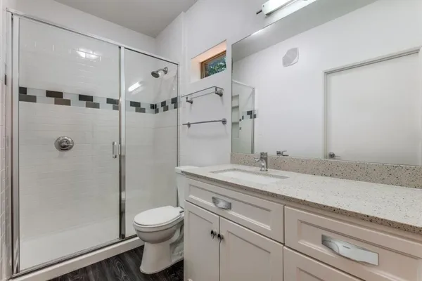 a bathroom with a granite countertop sink a toilet and shower