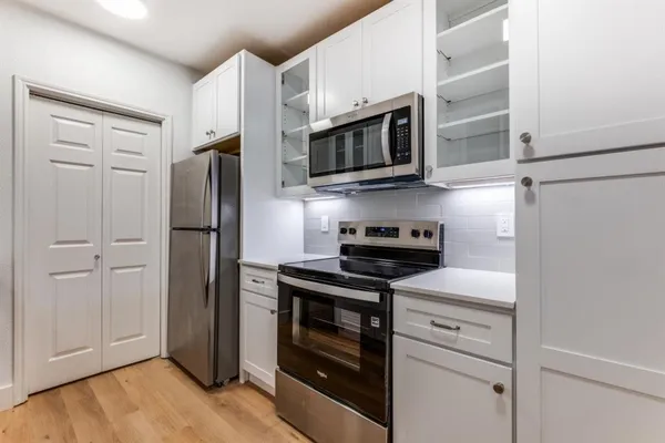 a kitchen with stainless steel appliances white cabinets white stove a microwave and a refrigerator