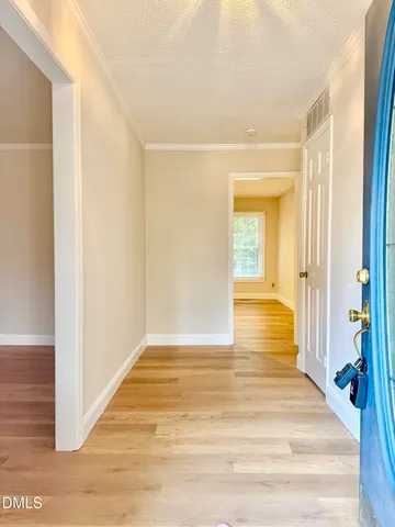 a view of a hallway with wooden floor and a bathroom