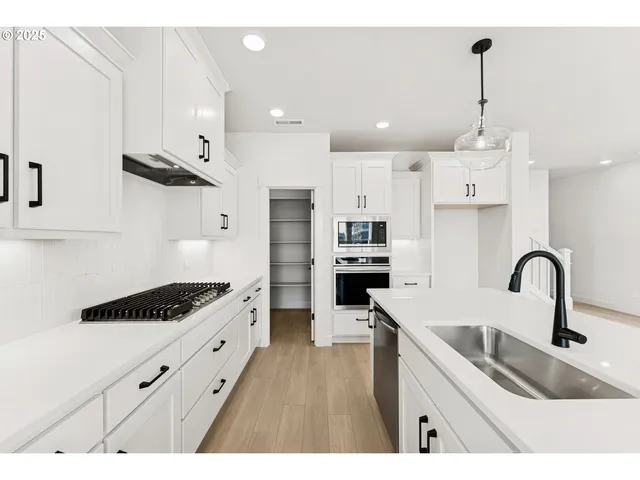 a kitchen with kitchen island stainless steel appliances a sink a stove and a wooden floors