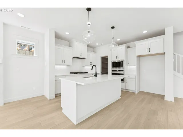 a large white kitchen with lots of counter space wooden floor and appliances