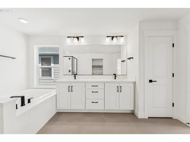 a bathroom with a double vanity sink mirror and bathtub