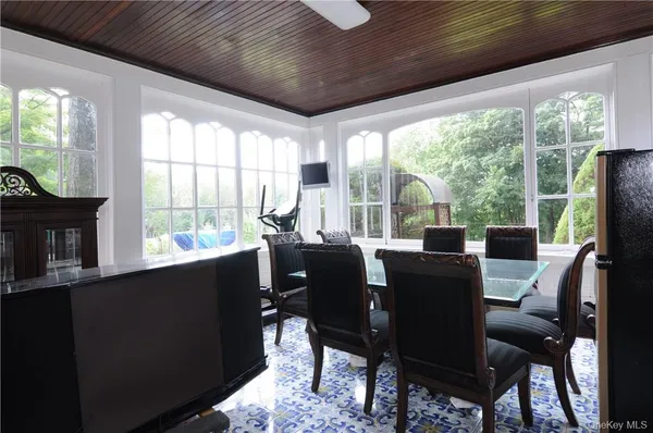 a dining room with furniture a flat screen tv and a floor to ceiling window