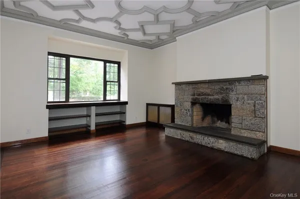 an empty room with wooden floor fireplace and windows