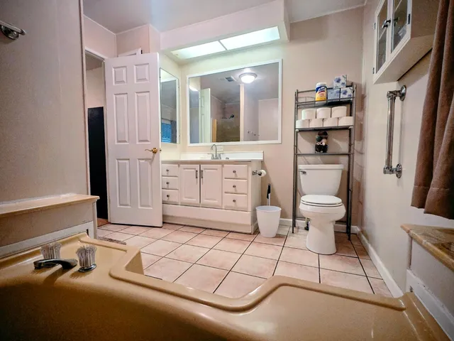 a spacious bathroom with a double vanity sink a toilet a mirror and shower