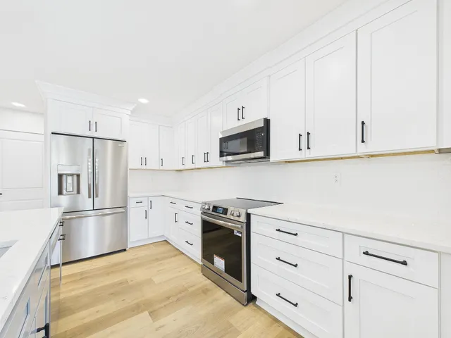 a large kitchen with kitchen island a stove a sink a center island and wooden floor