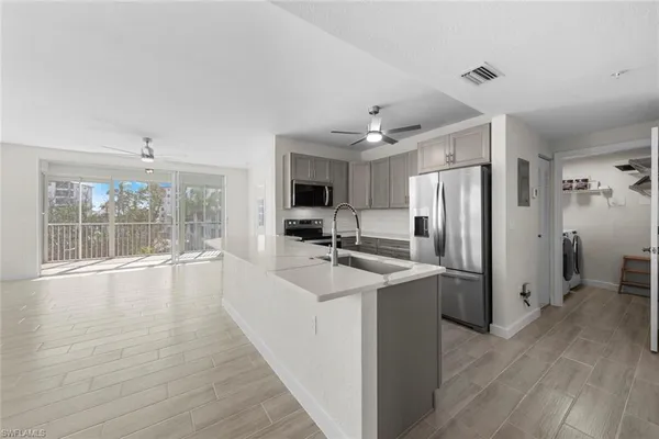 a view of a kitchen with a sink refrigerator and wooden floor