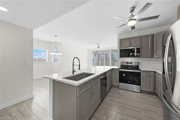 a kitchen with stainless steel appliances granite countertop a sink a stove top oven a refrigerator with island and chairs