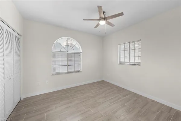 an empty room with wooden floor chandelier and windows