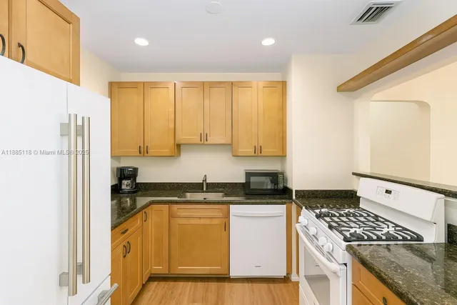 a kitchen with stainless steel appliances granite countertop a stove a sink and a refrigerator