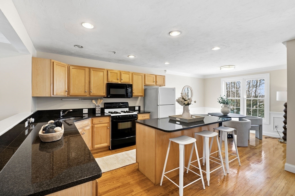 52 Packards Lane, Unit 4 Quincy, MA 02169 - Photo 3 of 40 a kitchen with stainless steel appliances granite countertop a stove top oven a sink a dining table and chairs with wooden floor
