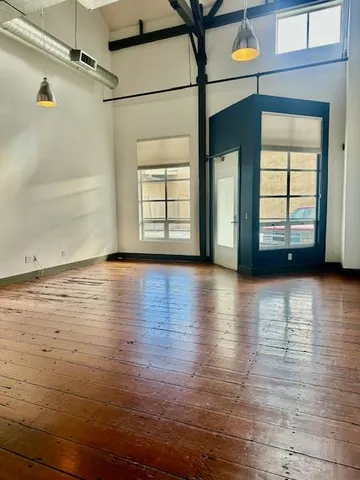 an empty room with wooden floor and windows with curtains