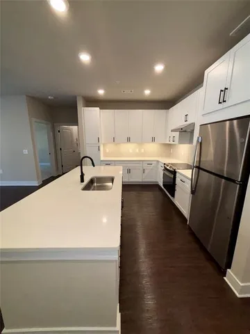 a large white kitchen with wooden floors and white stainless steel appliances