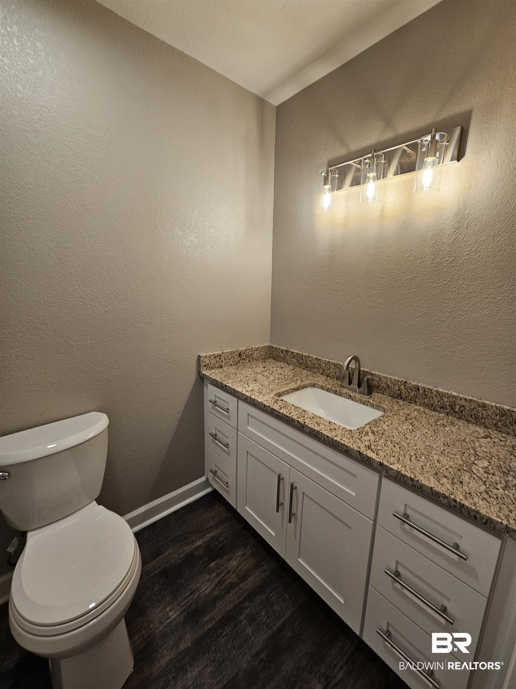 138 Wicker Way Daphne, AL 36526 - Photo 14 of 32 Half bath featuring a textured wall, vanity, and dark wood-type flooring