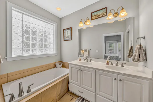 a bathroom with a granite countertop sink a large mirror a vanity and a bathtub